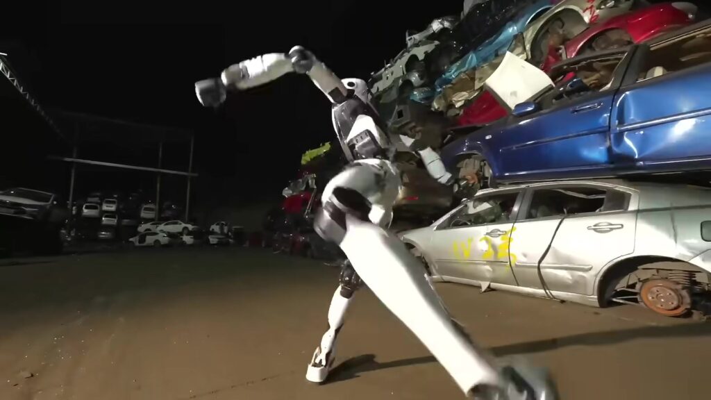 H2-X in a martial arts kick next to wrecked cars (Unitree Robotics, official video)